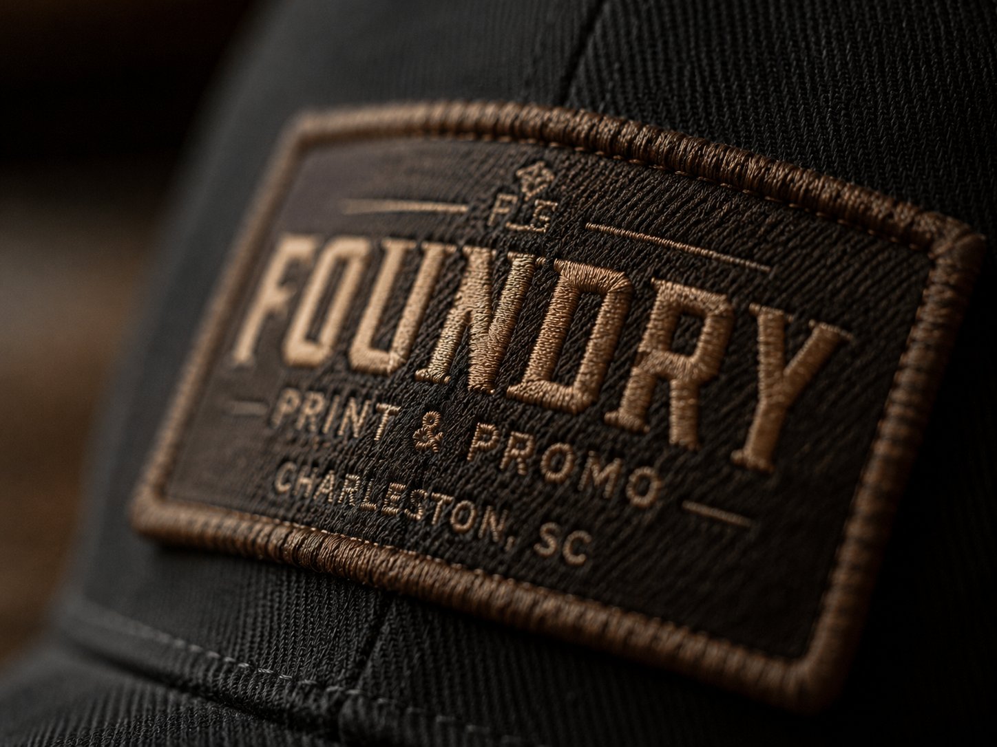 Macro close-up of embroidered Foundry Print and Promo patch on a hat — Charleston, SC